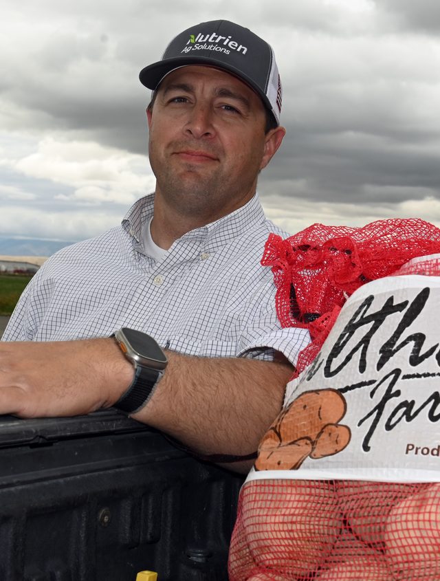 A Wray Farms grower leaning on a truck bed beside a sack of potatoes