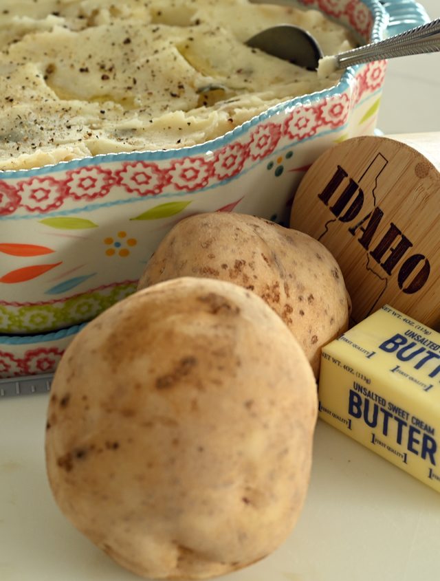 Fresh Idaho potatoes beside a dish of mashed potatoes and a stick of butter